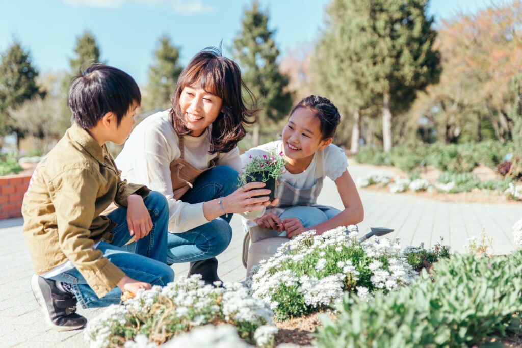 DIYで自宅の庭に人工芝や花などを植える家族の姿